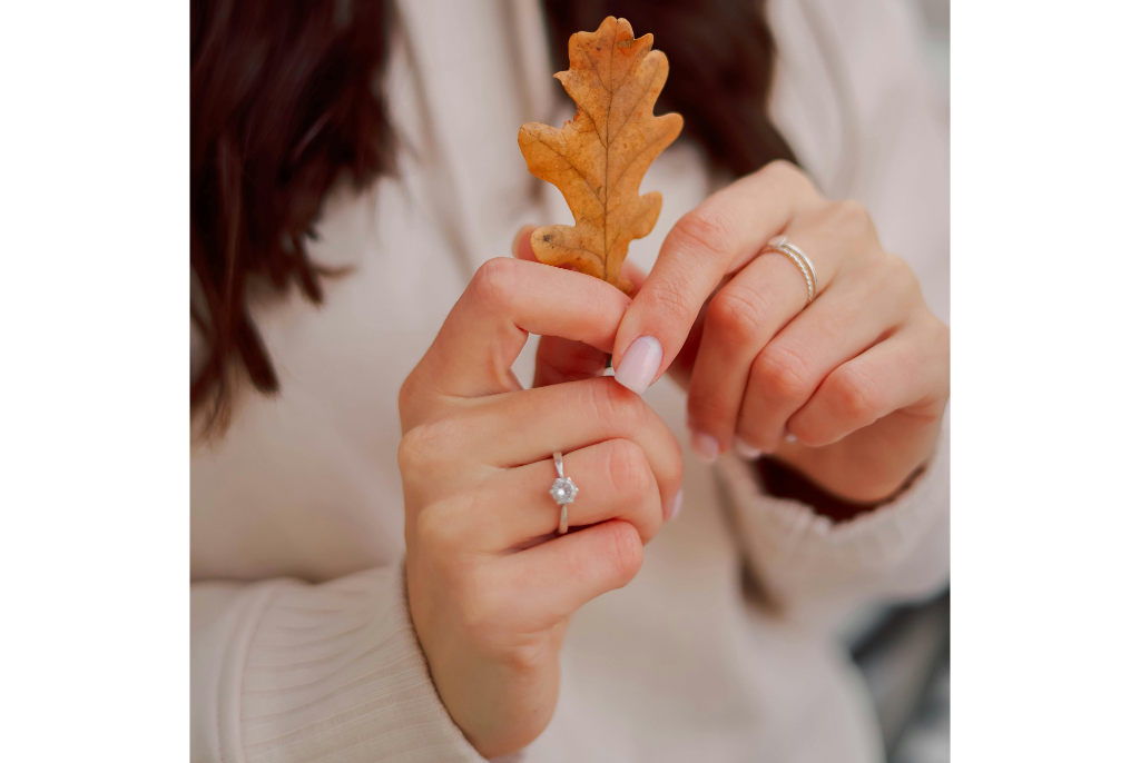 Mains avec manucure d’hiver en blanc nacré et décorations argentées, effet givré.