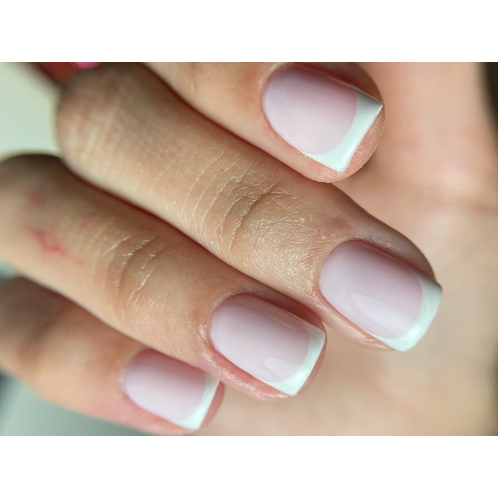 Ongles courts avec French manucure rose pâle et bord blanc net.
