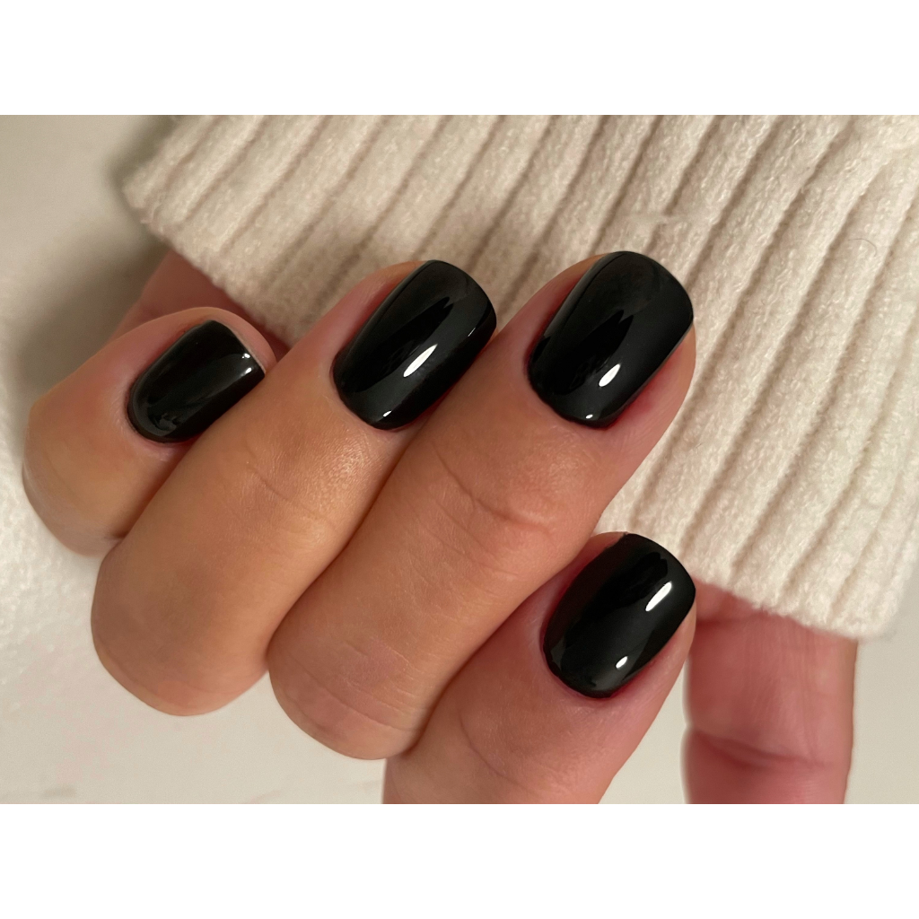 Ongles courts en gel noir brillant, manucure soignée et uniforme.